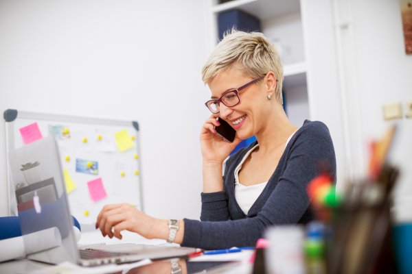 Woman At Desk On Phone Smiling