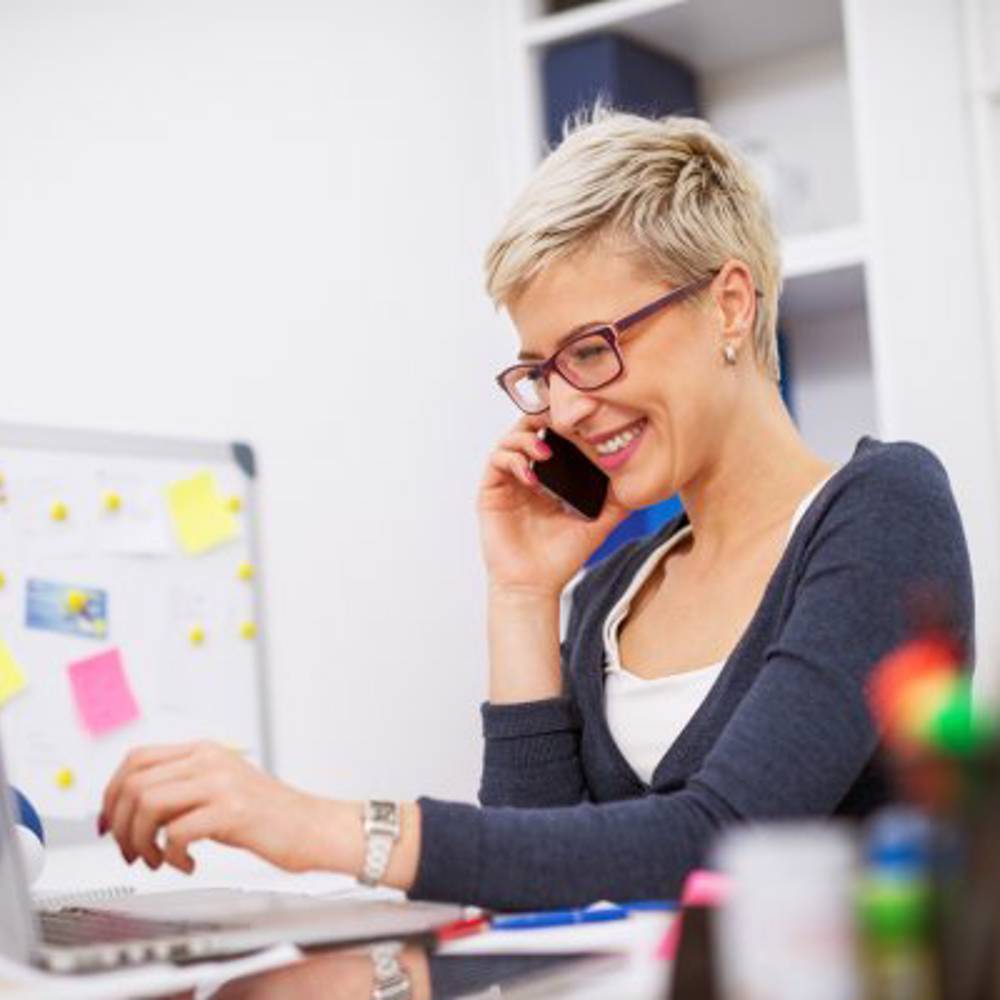 Woman At Desk On Phone Smiling