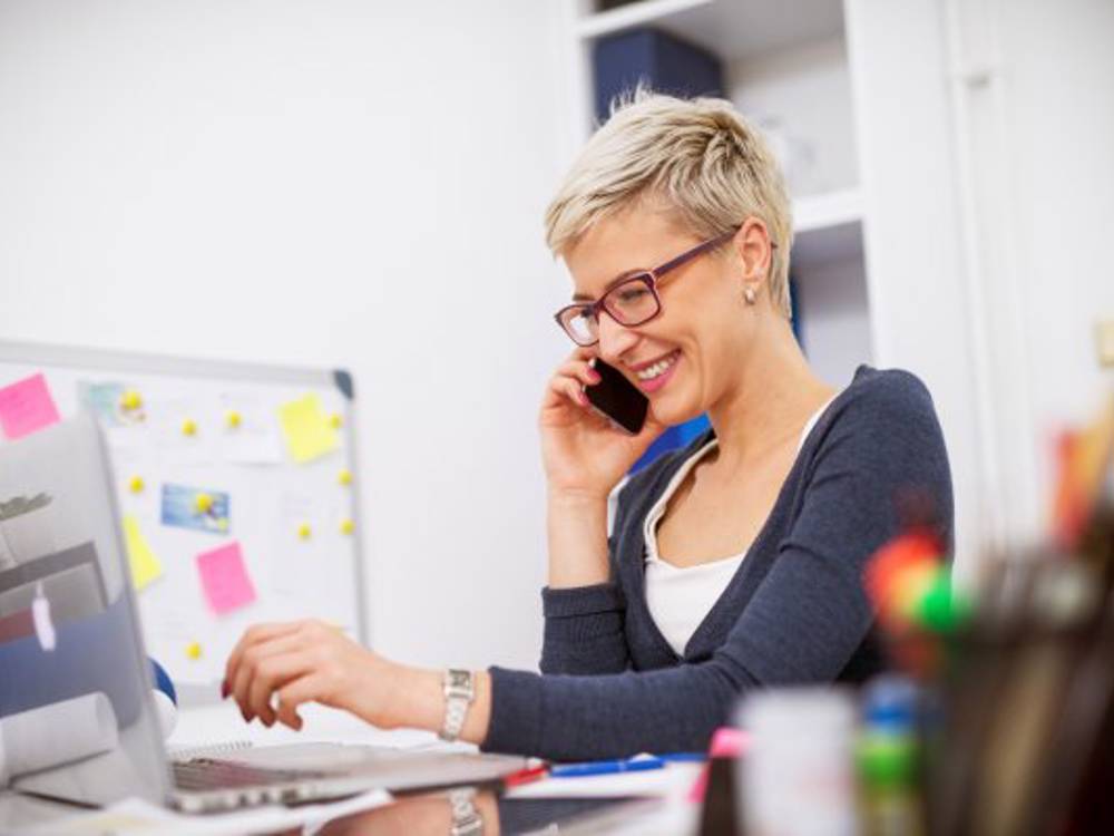 Woman At Desk On Phone Smiling
